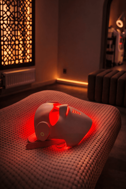 Led mask som används för ljusbehandling med rött ljus, placerad på en bäddad yta.