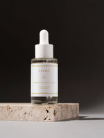 Prebiotics Jelly Serum i en flaska på en stenplatta.