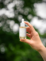 Prebiotics Jelly Serum i en hand med grön bakgrund, perfekt för att stärka hudens barriär och mikrobiom.