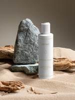 Flaska av Purifying Toner på sand och sten, designad för ren och balanserad hud.